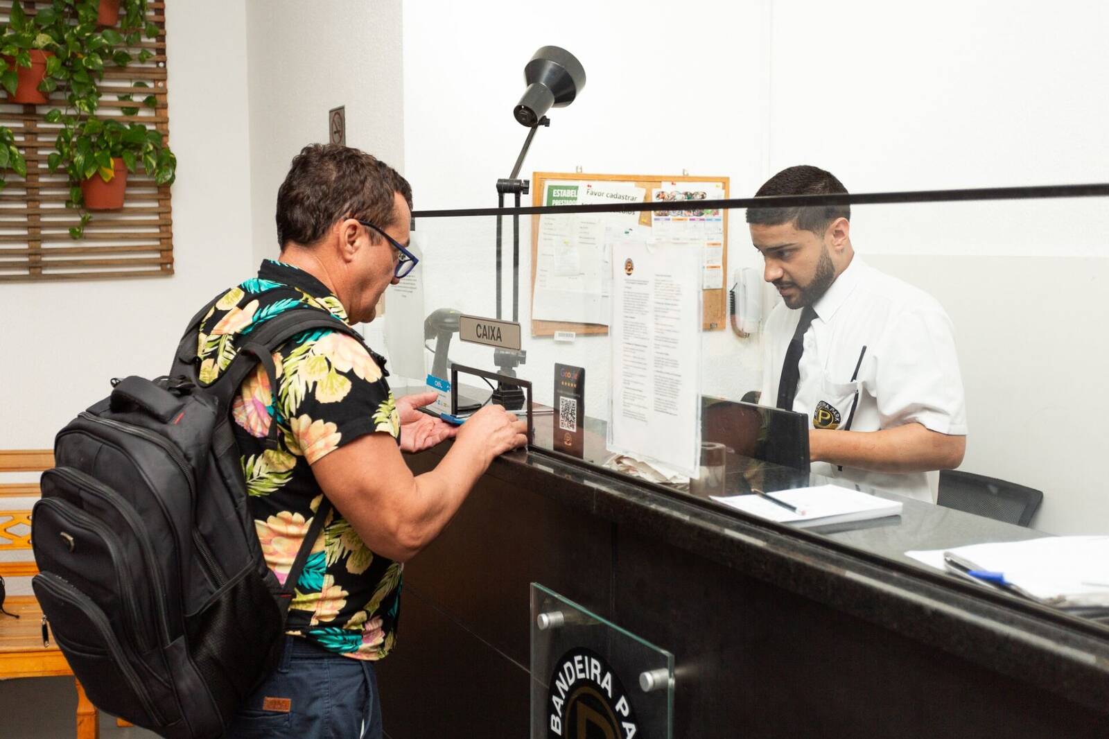 Empleada atendiendo a un cliente en el mostrador de Bandeira Park Congonhas